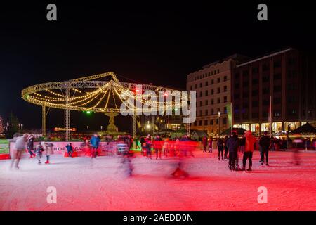 Nachtsicht der Menschen genießen in der Weihnachtsmarktsaison Eislaufen auf der temporären Eisbahn am Corneliusplatz und am Schalenbrunnen in Düsseldorf. Stockfoto