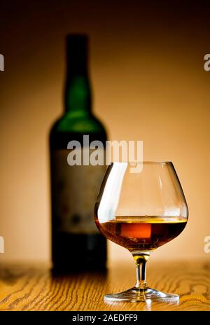 Ein Glas Cognac und Flasche im Hintergrund Stockfoto