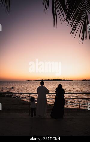 Arabische Familie, die an der Corniche in Jeddah, Saudi-Arabien, beobachten die schöne und farbenprächtige Sonnenuntergang Stockfoto