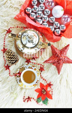 Weihnachtsbaumschmuck in einer Box, Big Red Star, künstlichen Kiefer und weihnachtsstern Blume, Red Star Kette, Teekanne und passende Teetasse auf Long Hair Teppich Stockfoto