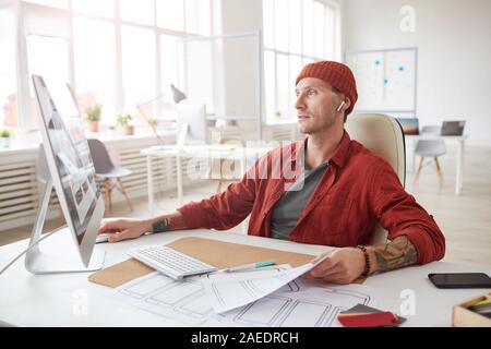 Portrait des modernen tätowiert Geschäftsmann mit Computer und Schreibtisch in leeren weißen Office arbeiten, kopieren Raum Stockfoto