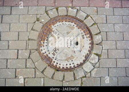 Antike Gusseisen rusty Mannloch auf Gehsteig Gehsteig der Straße der Stadt. Detail der städtischen Straße Stockfoto