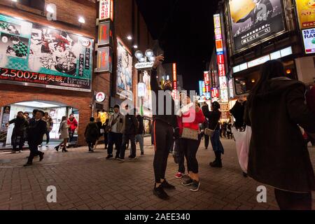 Eine Gruppe asiatischer Touristen nimmt Selfies im Centre Gai Shibuya, Tokio, Japan, auf. Stockfoto