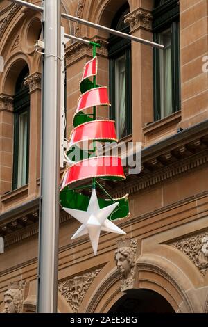 Sydney Australien, Weihnachten Dekorationen hängen von Lichtmasten in Martin Place mit Sandstein Gebäude im Hintergrund Stockfoto