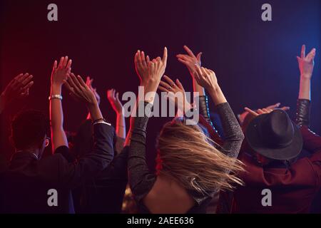 Zurück Blick auf junge Leute springen und heben die Hände beim Genießen Partei in verrauchten Nachtclub, kopieren Raum Stockfoto