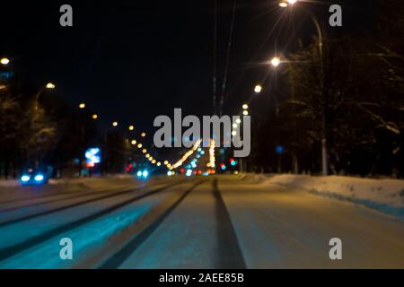 Nacht city street in die Ferne mit Schnee mit einer Tiefe Spur auf der Fahrbahn bedeckt. Untätigkeit der Straße Dienstleistungen führt zu Notfällen Stockfoto