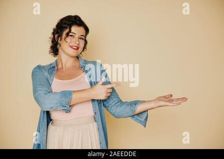 Portrait von lächelnden schöne junge Frau, etwas Interessantes auf Ihre Hand Stockfoto