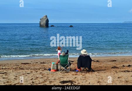 Paar sitzen auf Stühlen am Strand, am Meer, im Süden Milton Sands, Devon, Großbritannien Stockfoto