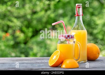 Frisch gepresster Orangensaft und in Scheiben geschnittenen Orangen auf einem Holztisch Stockfoto