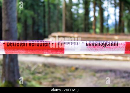 Rot-weiß gestreifte Warnung Absperrband in Wald sagen 'nicht geben' und 'Zorn zu leben" in deutscher Sprache Stockfoto