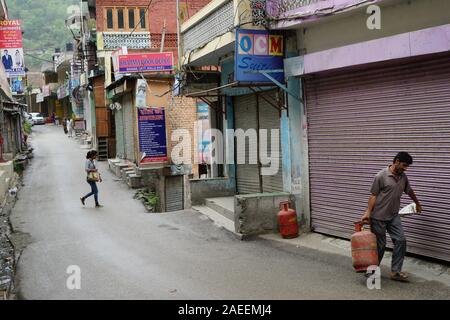 Mann, der Treibgasflasche in schmalen Straße, Banjar Stadt, Tirthan Tal, Kullu, Himachal Pradesh, Indien, Asien Stockfoto