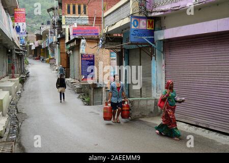 Mann, der Treibgasflasche in schmalen Straße, Banjar Stadt, Tirthan Tal, Kullu, Himachal Pradesh, Indien, Asien Stockfoto