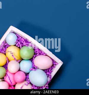 Multicolor Eier in einem weißen Fach kreative Ostern Konzept. Modernen soliden klassischen blauen Hintergrund. Platz Stockfoto