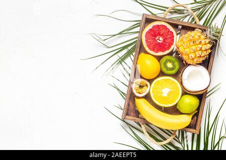 Tropische Früchte und Palmblättern auf einem weißen Hintergrund, Ansicht von oben. Stockfoto