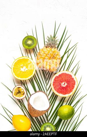 Tropische Früchte und Palmblättern auf einem weißen Hintergrund, Ansicht von oben. Stockfoto