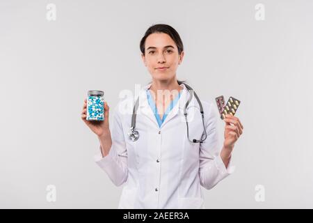 Hübsche junge weibliche Klinikpersonal in Jungtieren Holding jar und Blasen mit Pillen Stockfoto