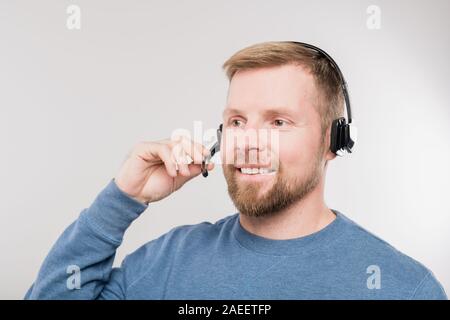 Junge freundliche hotline Betreiber im Headset und blauen pullover Consulting Kunden Stockfoto