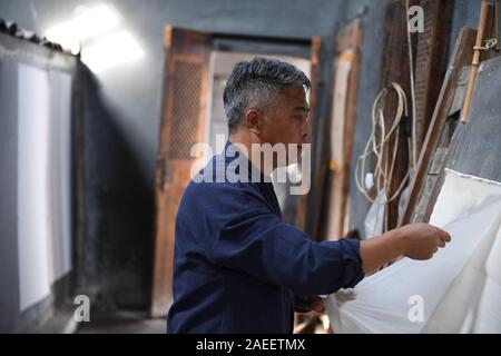 (191209) - JINGXIAN, Dez. 9, 2019 (Xinhua) - Cao Jianqin bereitet Xuan Papier an der Zijinlou Xuan Papier Fabrik in Jingxian Grafschaft, Stadt Xuancheng der ostchinesischen Provinz Anhui, Okt. 22, 2019 zu trocknen. Xuan Papier, traditionelle Chinesische Papier in Jingxian Grafschaft Xuancheng Stadt gemacht, hat eine Geschichte von mehr als 1.000 Jahren. Durch über 100 Verfahren, der das Papier kostet mindestens ein Jahr das Material in das endgültige Produkt zu machen. Für den "Distinguished Handwerk bekannt, feine Qualität und lange Zeit zu bewahren, das Papier ist von chinesischen Künstlern und Kalligraphen geliebt und heißt "pap Stockfoto