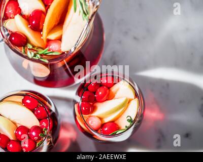 Winter Sangria auf der Tischplatte mit grau Leinen Tischdecke. Gläser Sangria mit Obst schneiden, Cranberry und Rosmarin. Kopieren Sie Platz für Text oder Design. Top View oder flach. Horizontale. Stockfoto