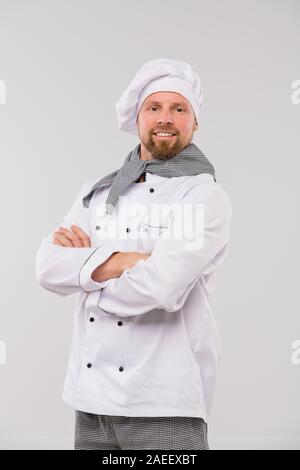 Erfolgreiche junge professionelle Küchenchef im Restaurant mit seinen Armen über der Brust gekreuzt Stockfoto
