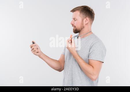 Junge professionelle Trainer mit Pfiff auf Stoppuhr während des Trainings Stockfoto