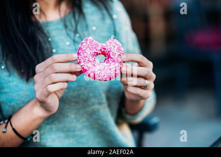 Frau ist Essen ein leckeres und farbigen Donut. Stockfoto