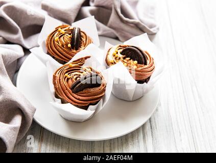 Kleine Kuchen oder Muffins mit Schokoladencreme auf weißem Holz- Hintergrund. Urlaub kuchen Feier, leckeres Dessert Stockfoto