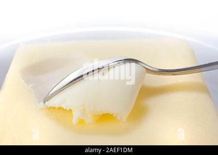 Butter in einer weißen Schüssel mit einem Metalllöffel Stockfoto