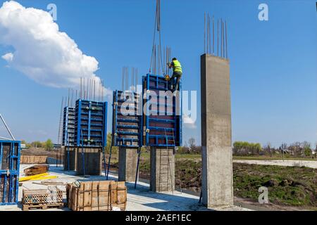 Die Schaffung der Basis der Hochhäuser mit speziellen Spalten. Stahlbetonstützen mit Bügeleisen Beschichtung stehen auf den großen Platten. Stockfoto