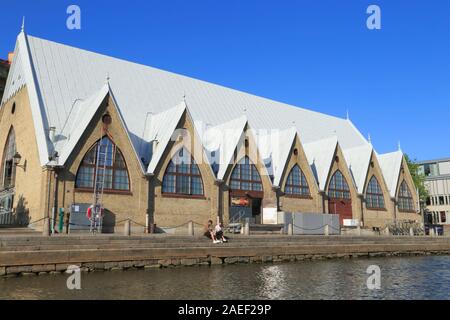 Ein paar sitzen außerhalb des Innen- Fischmarkt Feskekörka (von Victor von Gegerfelt ausgelegt) im Stadtzentrum von Göteborg in Schweden, im Sommer. Stockfoto