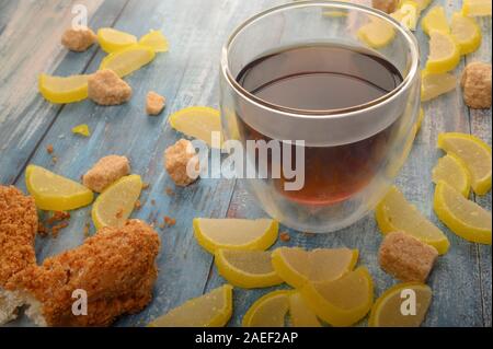 Ein Glas schwarzen Tee, Kuchen und Marmelade Zitronenscheiben auf einer hölzernen Hintergrund Stockfoto
