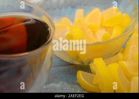 Marmelade Zitronenscheiben und einem Glas schwarzen Tee auf einem hölzernen Hintergrund. Süße Nachspeise. Nahaufnahme Stockfoto