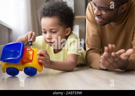 Smart little Kid Fix Spielzeugauto spielen mit Papa Stockfoto