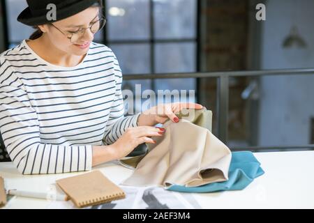 Hübsche junge Modedesigner auf Stück Textil, während Sie Fabric Stockfoto