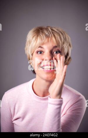 Frau mit kurzen blonden Haaren, Klatsch Geste. Menschen und Emotionen Konzept Stockfoto