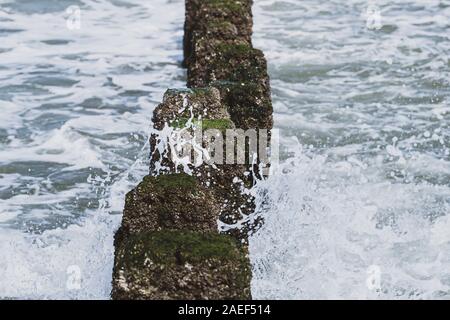 Sea Wave übergelaufen durch eine hölzerne groyne am Strand. Stockfoto