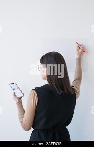 Ansicht der Rückseite des eleganten Geschäftsfrau oder Trainer mit Smartphone, Präsentation Stockfoto
