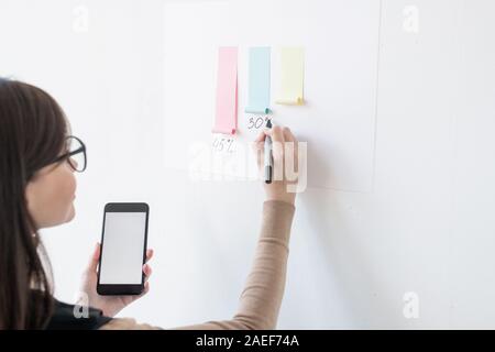 Junge weibliche Broker aufschreiben Prozentsatz unter Papier Chart auf dem Whiteboard Stockfoto