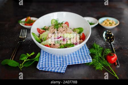 Einem hohen Winkel Nahaufnahme von einem weißen Keramik Schüssel voll mit frischen Thunfisch Salat. Schuß auf eine rustikale Metall Hintergrund. Stockfoto