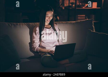 Foto von chinesischen Frau notebook Knie texting Kollegen Nachtarbeiter durchsuchen verrückt süchtig Workaholic bequemen Sofa legere Kleidung sitzen Stockfoto