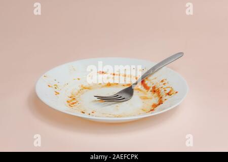 Ein Teller mit Resten von Tomatensauce. Ungewaschen Gerichte illusatration, schmutzige Teller auf hellen Hintergrund Stockfoto