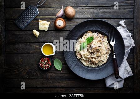 Risotto mit Pilzen in einer schwarzen Platte über rustikal Hintergrund, Ansicht von oben Stockfoto