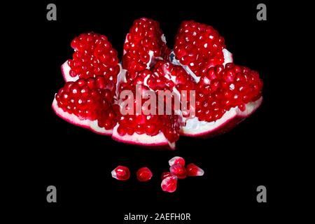 Reifer Granatapfel Obst mit leuchtend roten Körnern auf einem schwarzen Hintergrund öffnen Stockfoto