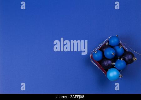Blau Christbaumkugel Kugeln und Girlande in der Box auf blauem Hintergrund. Ansicht von oben Stockfoto