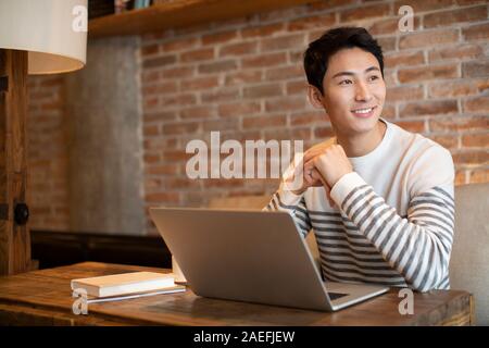 Junger Mann mit Laptop im Coffee Shop Stockfoto