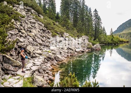 Frau Touristen sitzen auf Stein auf Morskie Oko See, Tatra, Polen Stockfoto