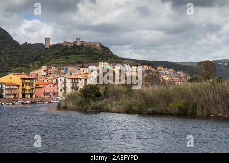 Die Wellen des Flusses Temo. Farbenfrohe Gebäude der Stadt im Hintergrund, zusammen mit einem grünen Berg mit einer Burg. Regnerisch trübe Frühlingshimmel. Bosa, Sa Stockfoto