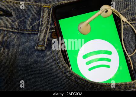 Mit Spotify Logo auf dem Bildschirm in der blauen Jeans Tasche mit Ohrhörer Telefon. Los Angeles, Kalifornien, USA - 13. Oktober 2019, Illustrative Editorial Stockfoto