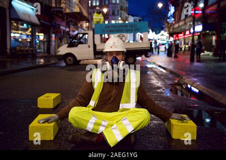 London, Großbritannien. 09 Dez, 2019. Aussterben Rebellion' Luft, die wir trauern' protestieren Demonstrant eine pre-dawn Aktion in Central London illegalen die Luftqualität in der Hauptstadt zu protestieren. Die Autobahn Wartung Arbeiter gekleidet, sie blockiert Cranbourne St und sich für konkrete Bausteine auch auf der Straße Credit geklebt geklebt: Gareth Morris/Alamy leben Nachrichten Stockfoto