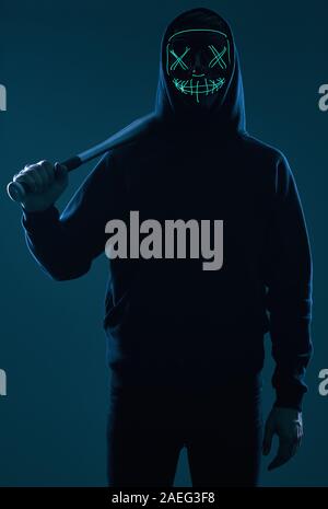 Porträt eines anonymen kriminellen Mann mit Baseballschläger in einer schwarzen Kapuze sein Gesicht hinter einer Maske. Studio gedreht. Stockfoto